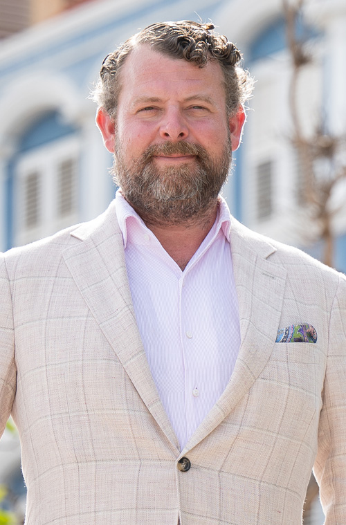 Mike Gray standing outside a row of colorful buildings